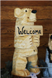 Wooden Statue of a Small Bear Holding a Welcome Sign
