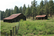 Barbed Wire Fence with Two Sheds and Trees in Background