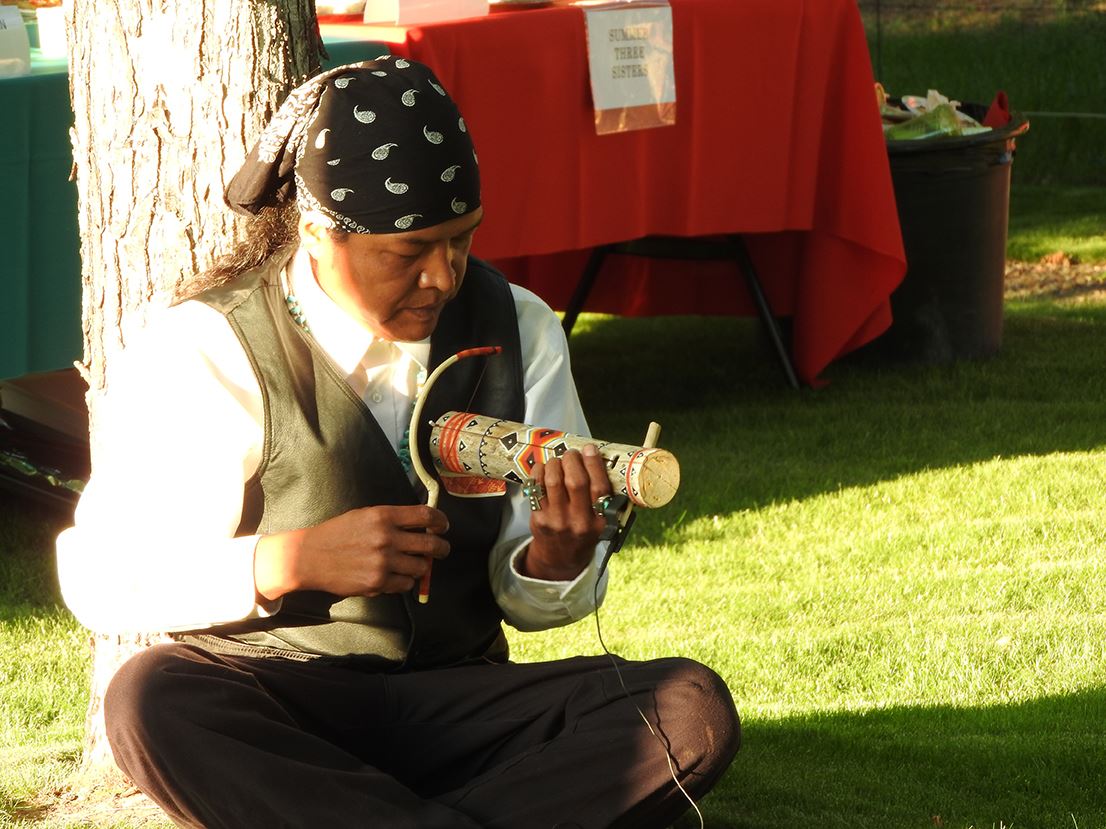 Man Sitting with Legs Crossed Playing an Instrument