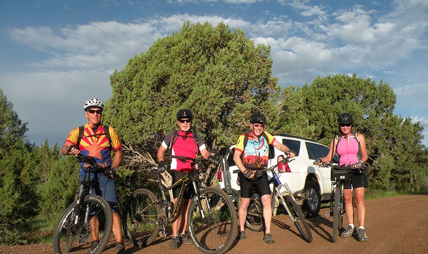 Four Bicyclists Standing by Their Bikes on a Dirt Road