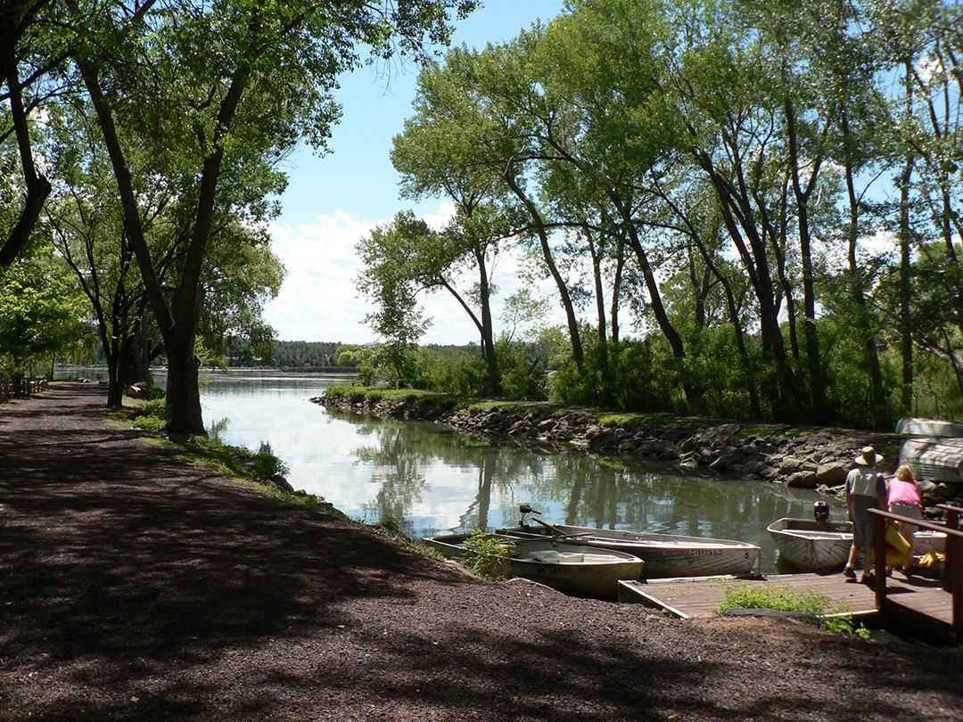People Standing on Lake Boat Dock Next to Several Small Boats